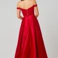 A woman is wearing the HOLLY PO819 - Size 12, a long, off-the-shoulder red gown from our Online Formal Wear Shop that features a fitted bodice and flowing skirt. The dress highlights a zipper down the back. With her long, dark hair cascading down her back, she faces away from the camera, beautifully showcasing the rear details of the gown. Angels Formal Wear