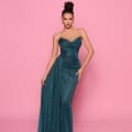 A woman wearing the elegant IZY NP149 teal strapless floor-length gown poses against a pink background. Her hair is styled in an updo, and she accessorizes with hoop earrings. The vibrant setting echoes the sunny vibes of Queensland’s Sunshine Coast. Angels Formal Wear