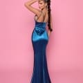 A woman with a long braid is wearing the form-fitting, floor-length ALLURE NP166 dress from Cocktail Dress Shop. The shiny blue dress features thin straps and she poses against a solid pink background, with one hand on her head and looking slightly to the side. Angels Formal Wear