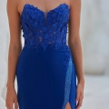 A person wearing a strapless, deep blue gown with intricate floral lace detailing on the bodice and a high slit adorned with rhinestones on the skirt. The background is light and blurred, highlighting the elegance of this BO PO2452 piece. Angels Formal Wear