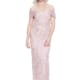 A smiling woman with gray hair is wearing an elegant, off-the-shoulder, light pink ALIYA DRESS - TL1114 with intricate beadwork. She is standing against a plain white background. Angels Formal Wear