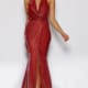 A woman stands wearing a shimmering red TIARNA JX2108 halter neck gown that features a plunging neckline and high slit. Her hair is slicked back, and she poses with one hand on her hip, against a plain white background. She wears high-heeled shoes. Angels Formal Wear