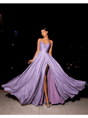 A woman wearing the flowing, sparkly STARLIGHT NC2029 lavender gown with a thigh-high slit poses against a dark background. Bathed in starlight, she stands confidently, holding out the sides of the dress to showcase its fabric and shimmer. She pairs the STARLIGHT NC2029 dress with high heels and has a serene expression. Angels Formal Wear