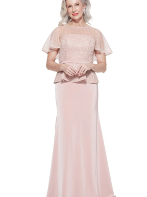 A woman stands wearing the FRANCESCA BEADED GOWN TL1159, a floor-length, short-sleeved evening dress in blush pink featuring a textured top and smooth skirt. With light-colored hair and a cheerful smile, she poses against a plain white background. Angels Formal Wear