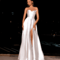 A woman stands gracefully outdoors at night, wearing an enchanting HAVANNA NC2030 strapless white satin gown with a sweetheart neckline and a high thigh slit. Her hair, styled straight and long, cascades over her shoulders. Poised and elegant on the patio, she evokes the timeless charm of HAVANNA under the moonlit sky. Angels Formal Wear